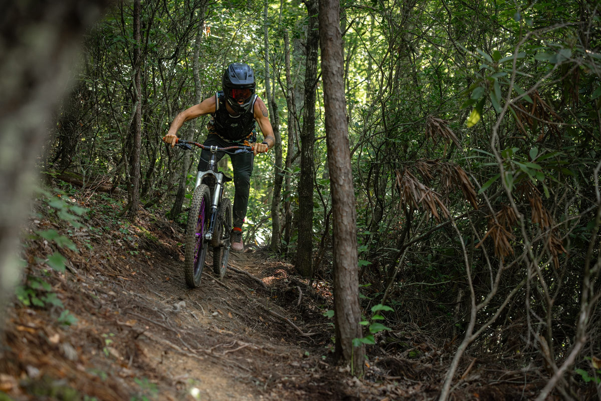Rider descending forest singletrack on the Invert Enduro inverted fork